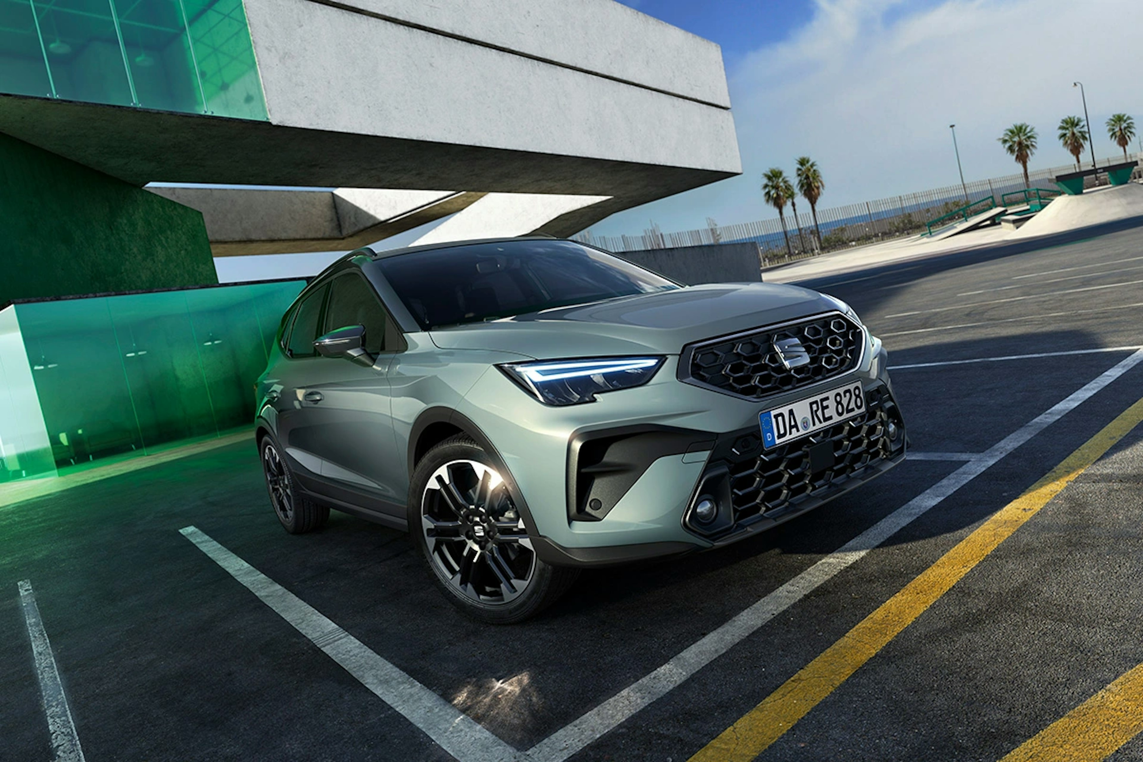 SEAT Arona in Oniric Lake vor grünem Glasgebäude auf leerem Parkplatz