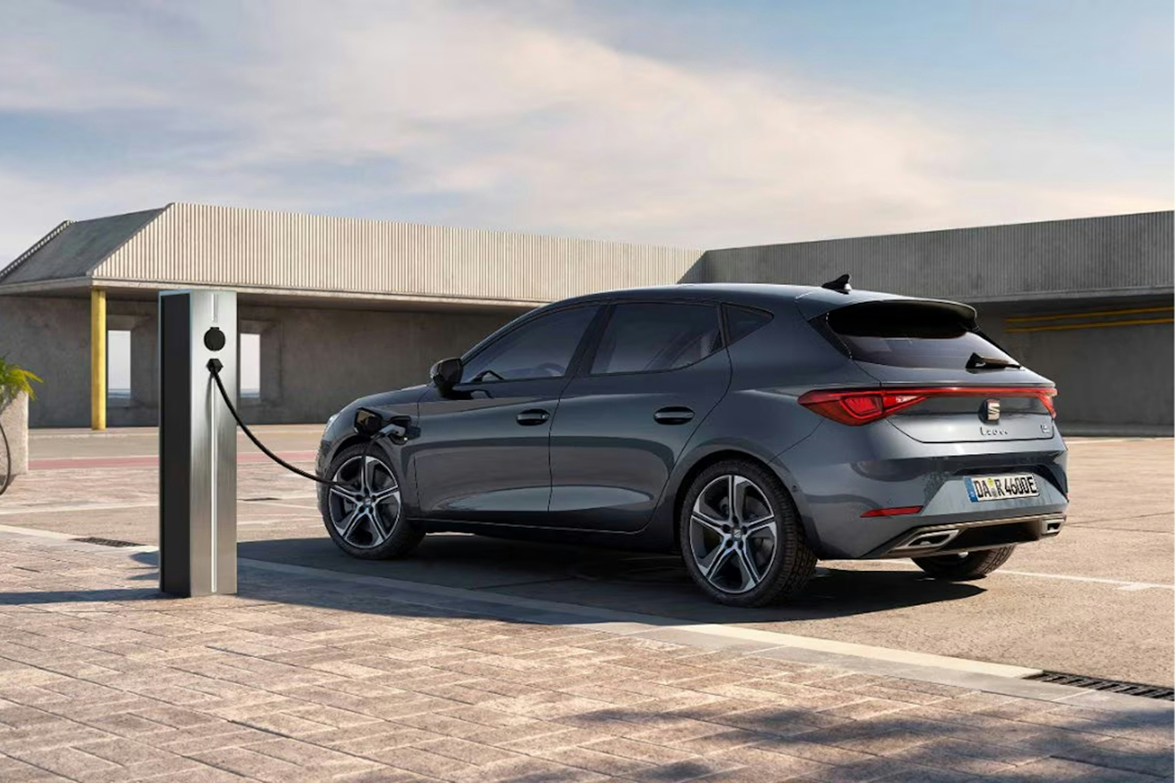 Ein SEAT Leon Sportstourer e-HYBRID lädt auf einem öffentlichen Parkplatz an einer Ladesäule.